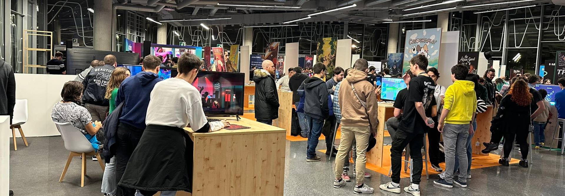 Una multitud de personas en un evento tecnológico disfrutando de diferentes pantallas y actividades.
