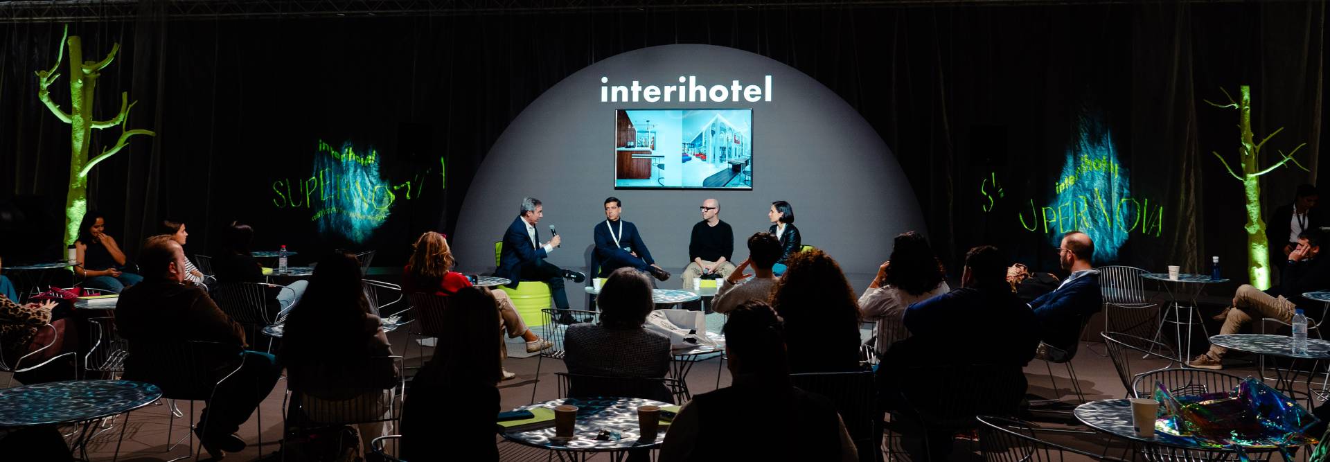 Una conferencia en un evento llamado InteriHotel con panelistas y un público atento.