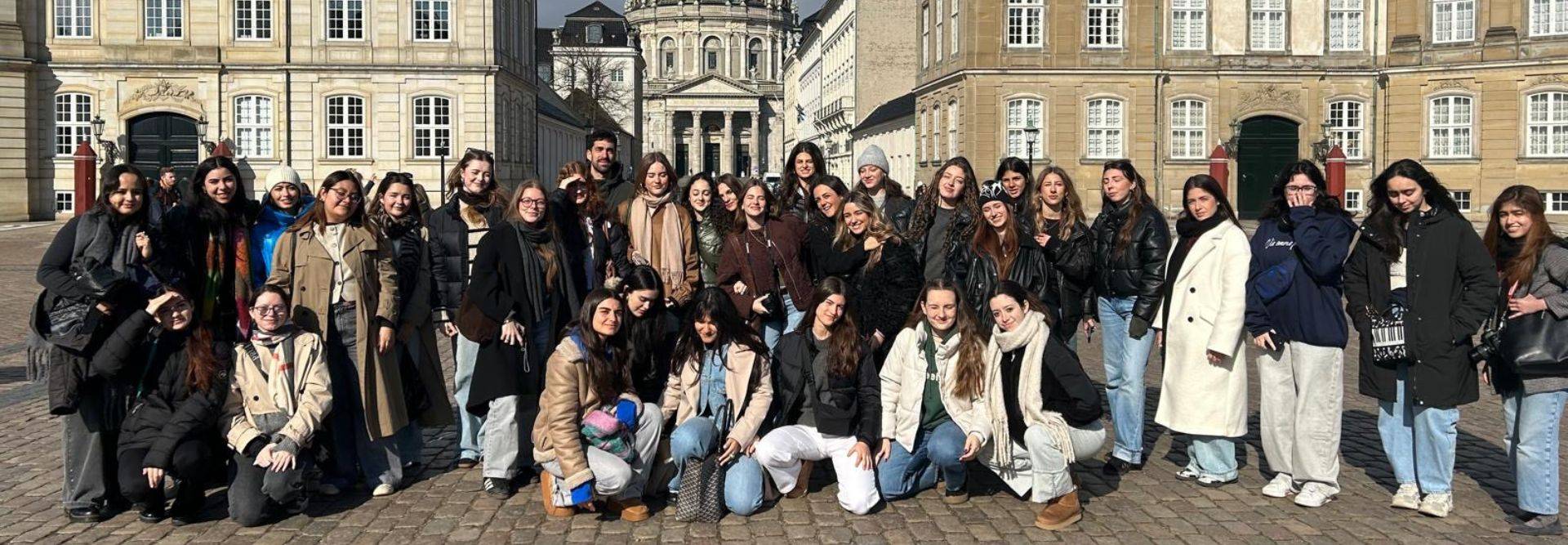 Un grupo de mujeres posando juntas frente a un edificio histórico en un día soleado.