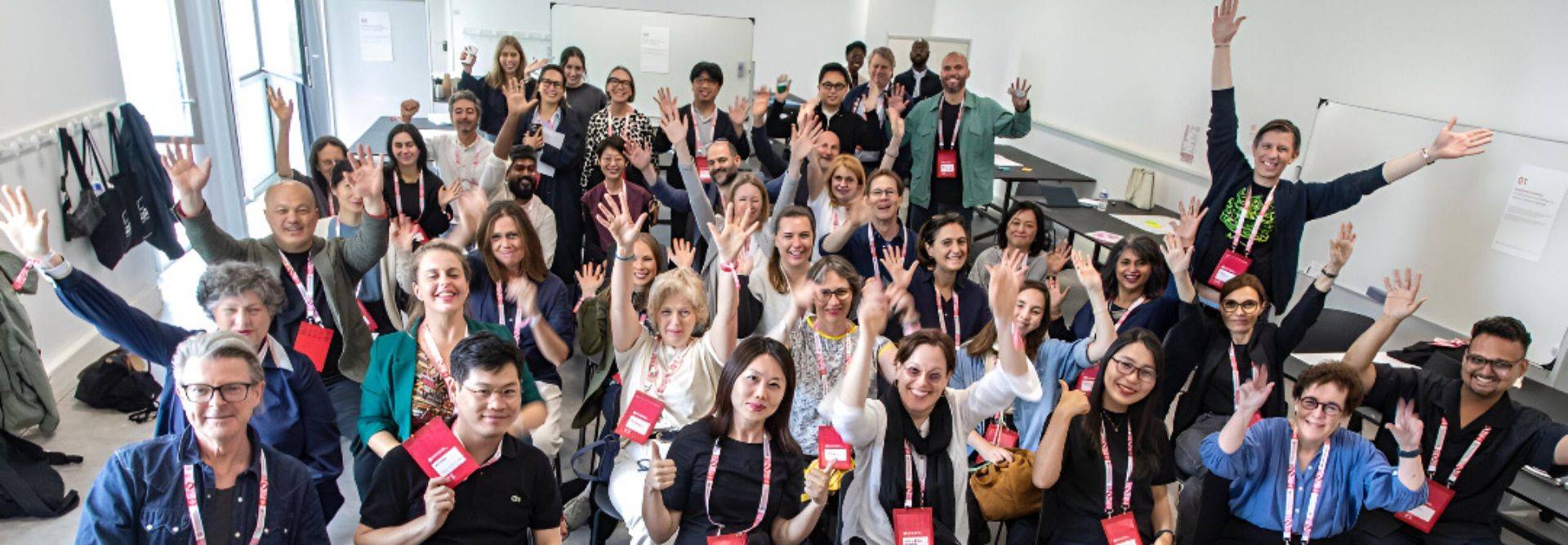 Una multitud sonriente de personas levantando las manos en un entorno de conferencia.