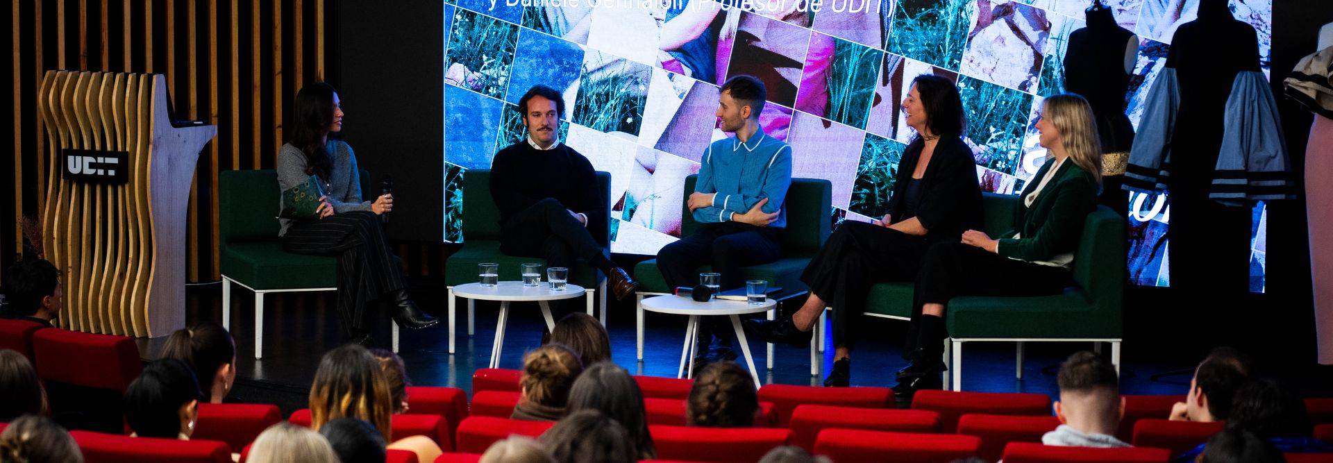 Un panel de discusión con cuatro oradores sentados en un escenario ante una audiencia.