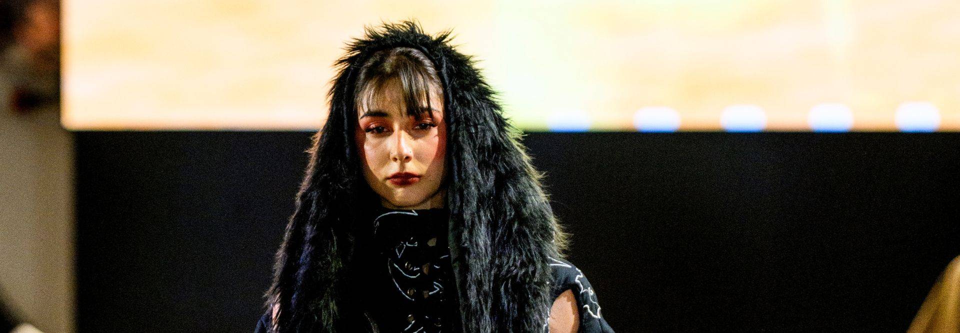 Una modelo presenta un look audaz con un abrigo de pelaje negro y maquillaje oscuro.