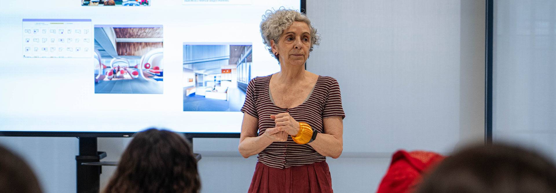 Una persona está dando una presentación frente a una pantalla en un entorno moderno.