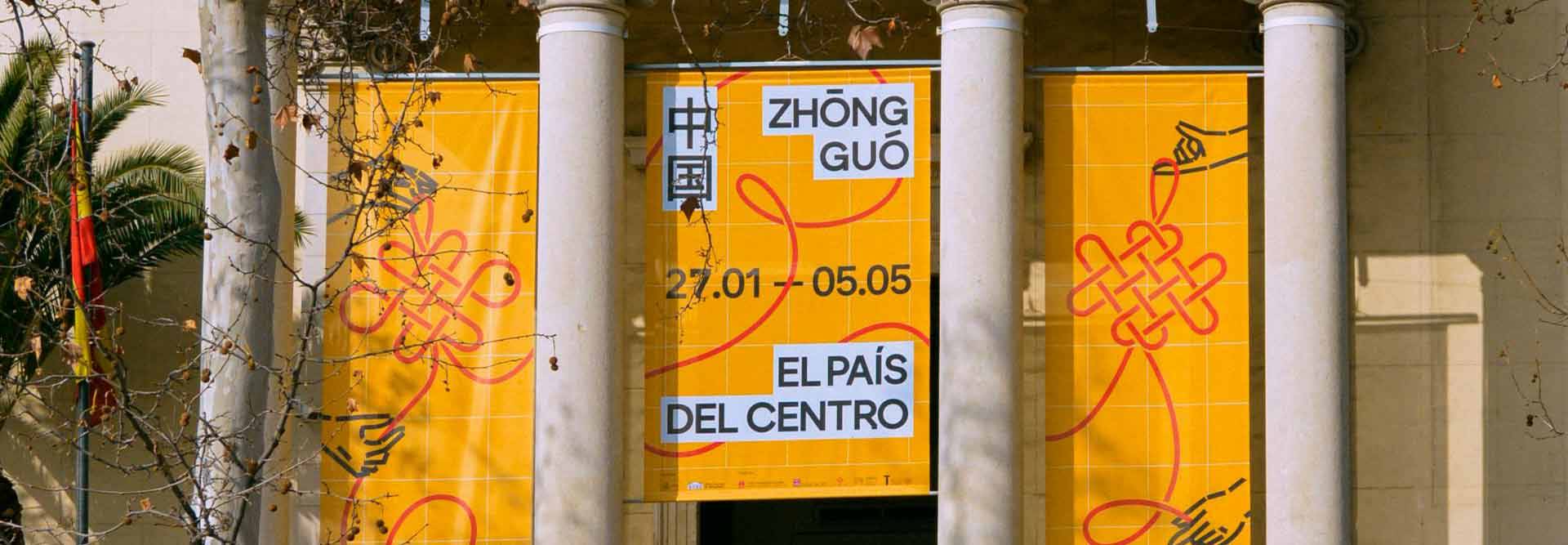 Se observa un cartel amarillo que anuncia una exposición sobre China en un edificio con columnas.