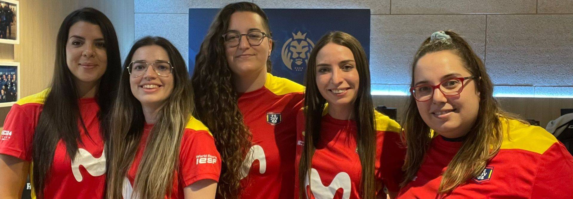 Grupo de cinco mujeres jóvenes vistiendo camisetas de un equipo deportivo.