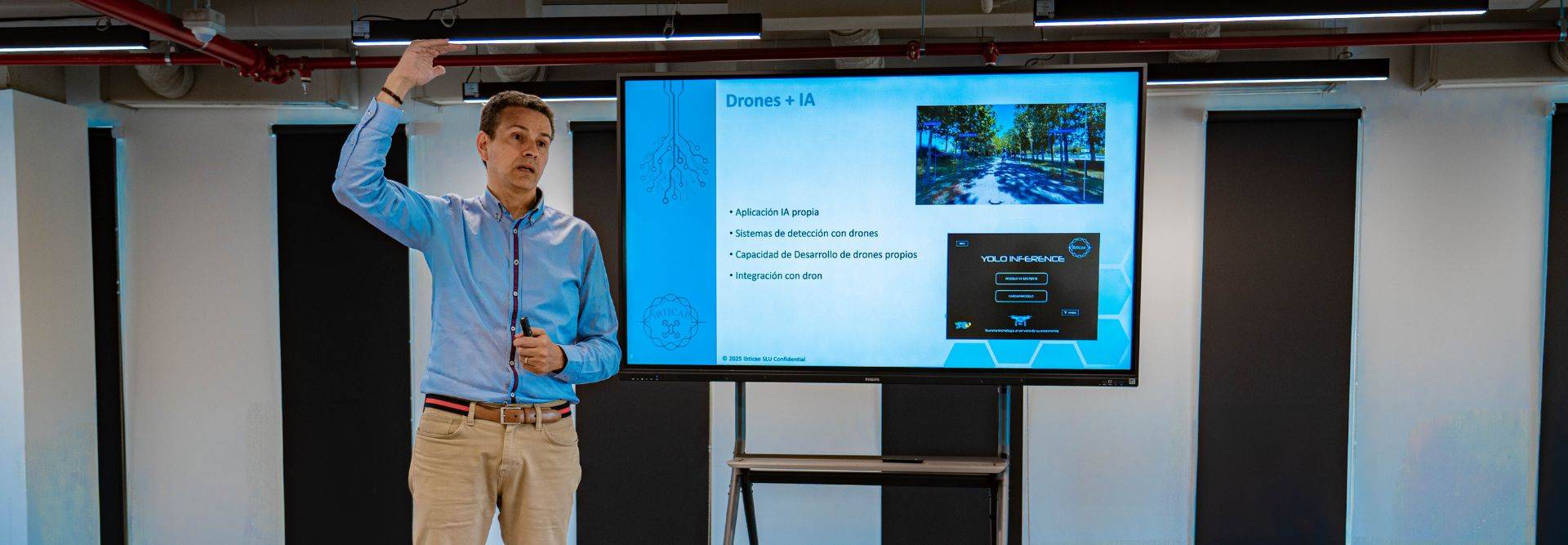 Un presentador explica el uso de drones en una sala con una pantalla de proyección.