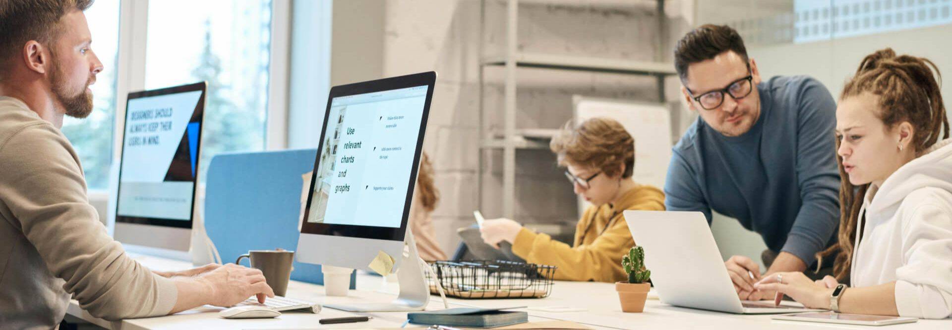 Un grupo de personas trabaja en un entorno de oficina moderno utilizando computadoras y laptops.