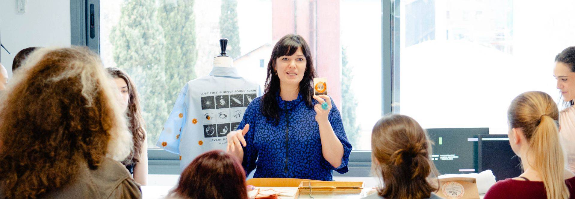 Una mujer está dando una presentación frente a un grupo de personas en un ambiente luminoso.