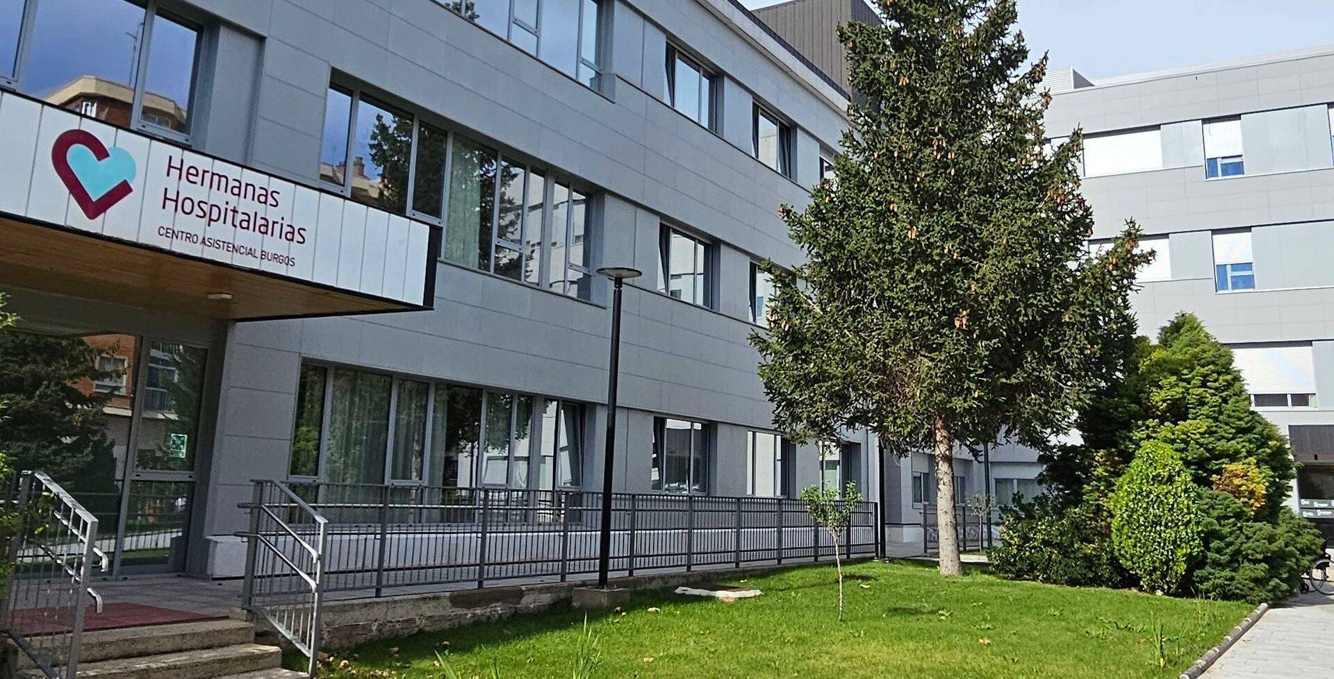 Edificio de un hospital con áreas verdes y árboles en el exterior.