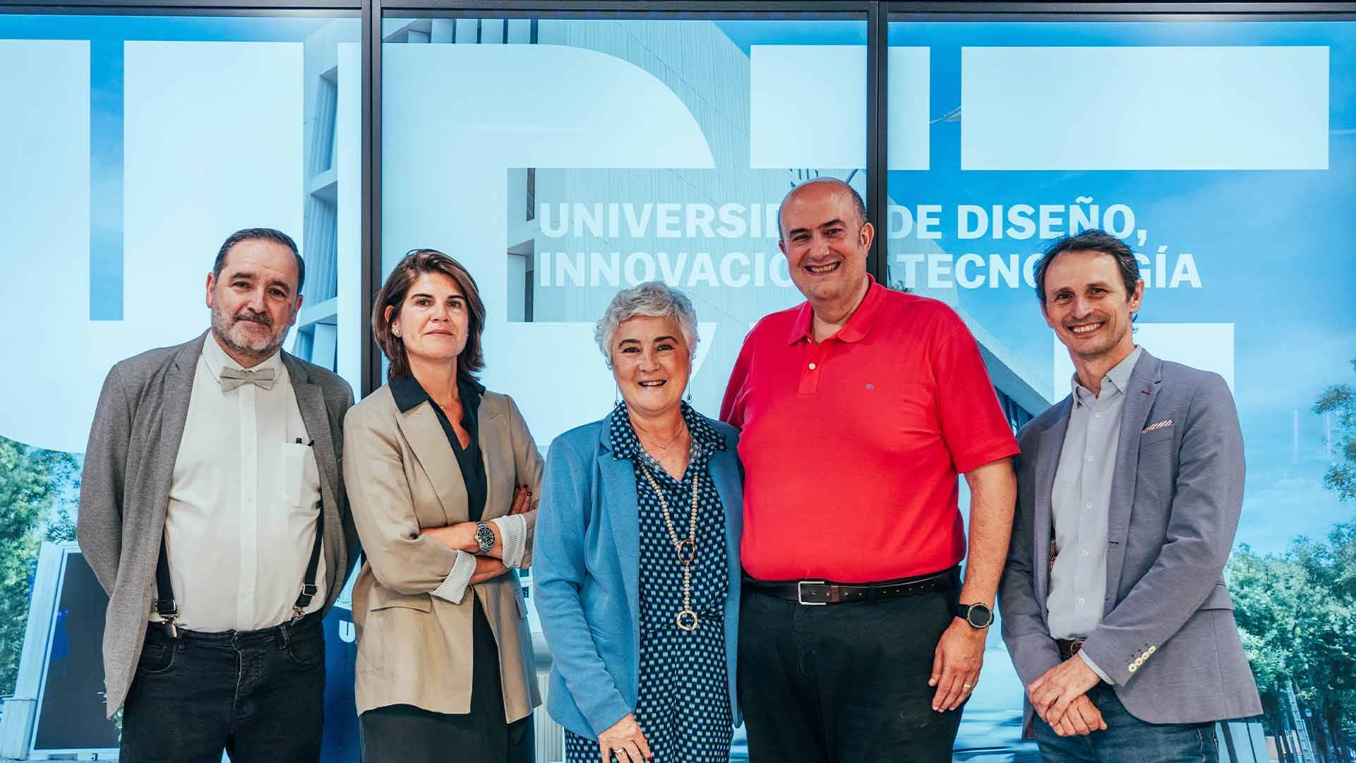 Un grupo de personas posando frente a un fondo con el logo de una universidad.