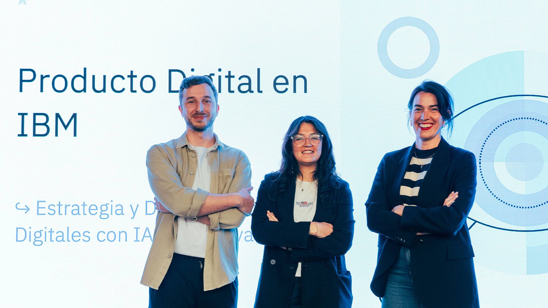 Tres personas posan frente a una presentación de Producto Digital en IBM.