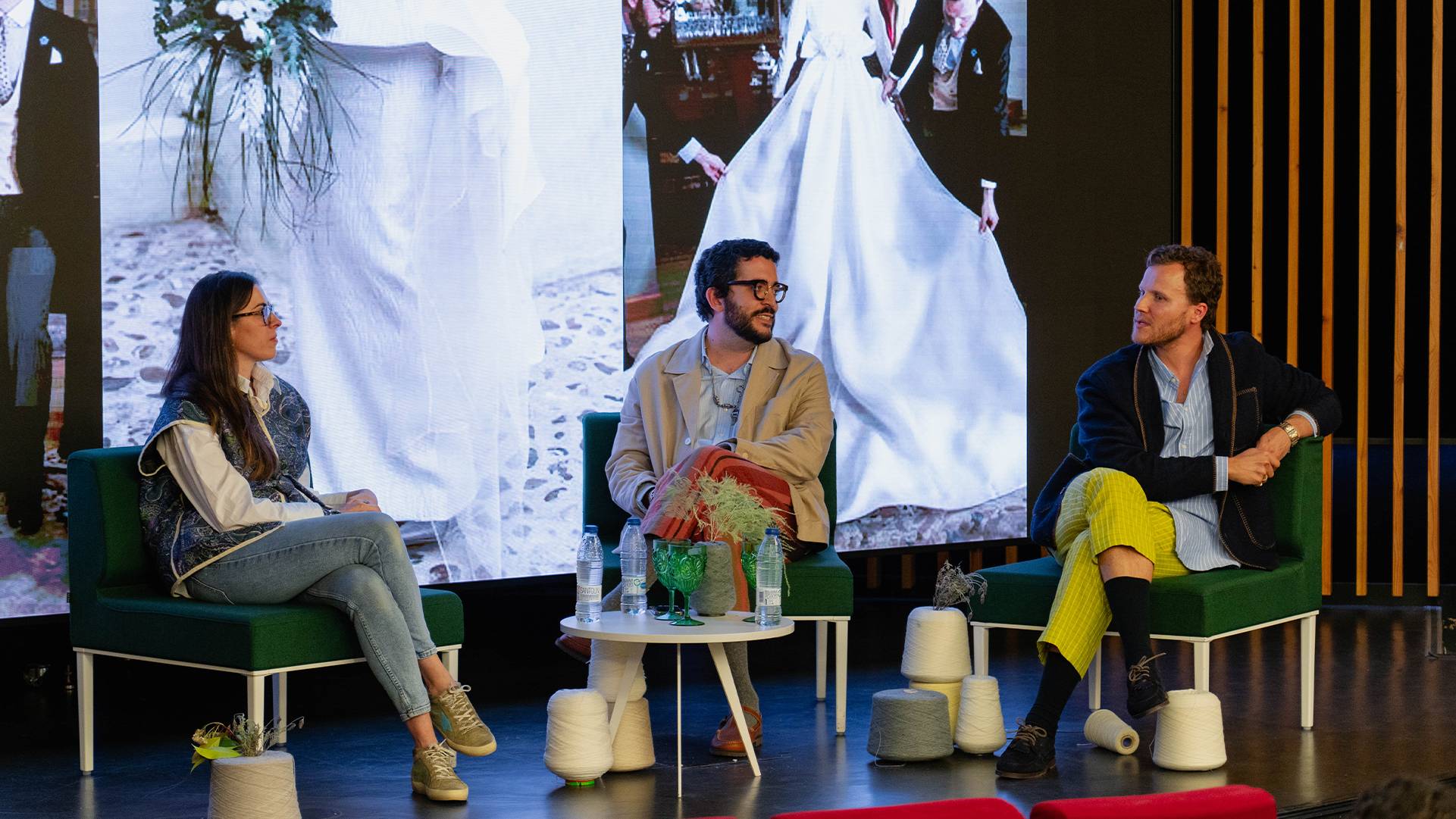 Un panel de tres personas discutiendo en un escenario con una proyección detrás.