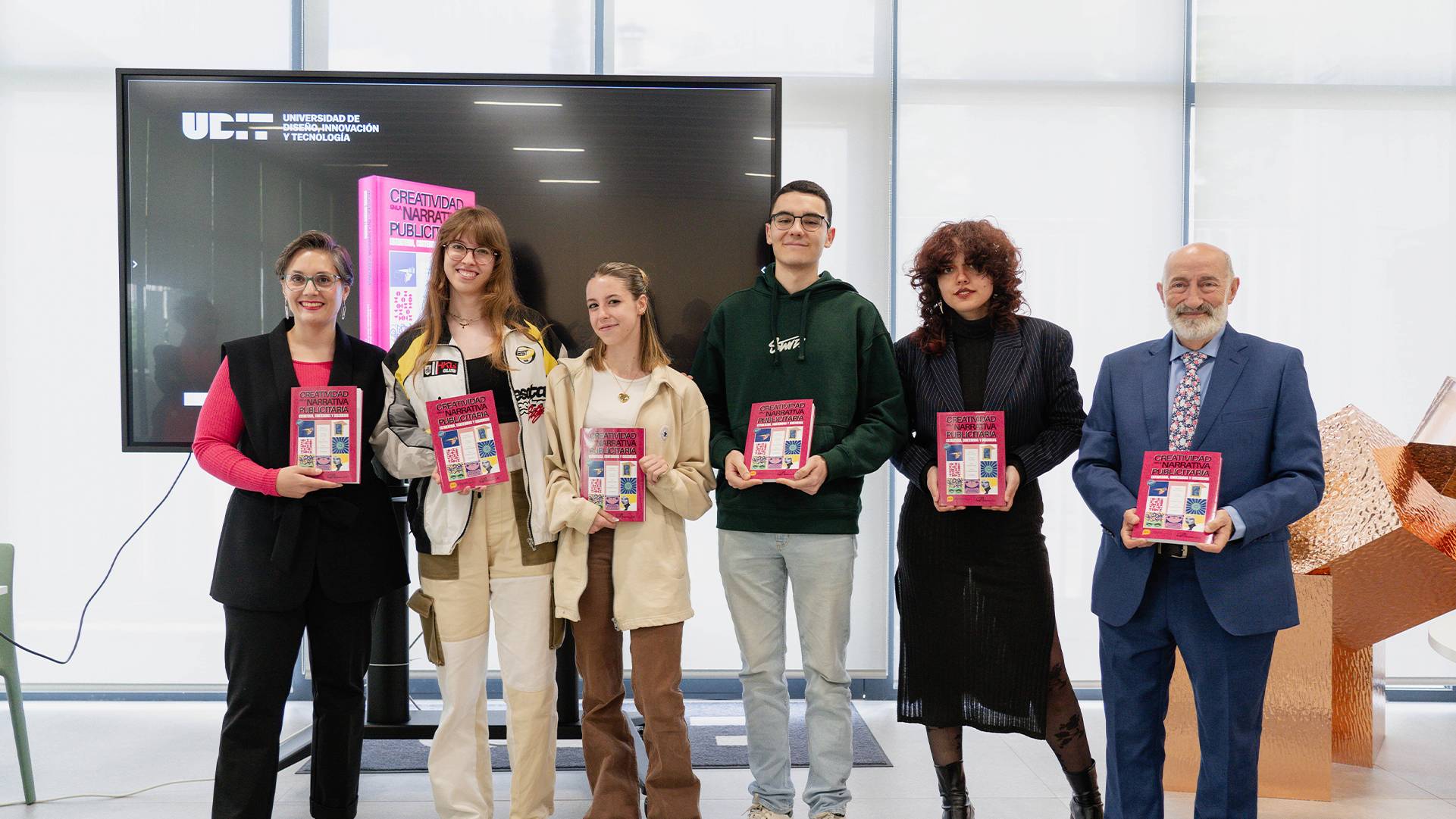 Grupo de jóvenes posando con libros en un evento educativo.