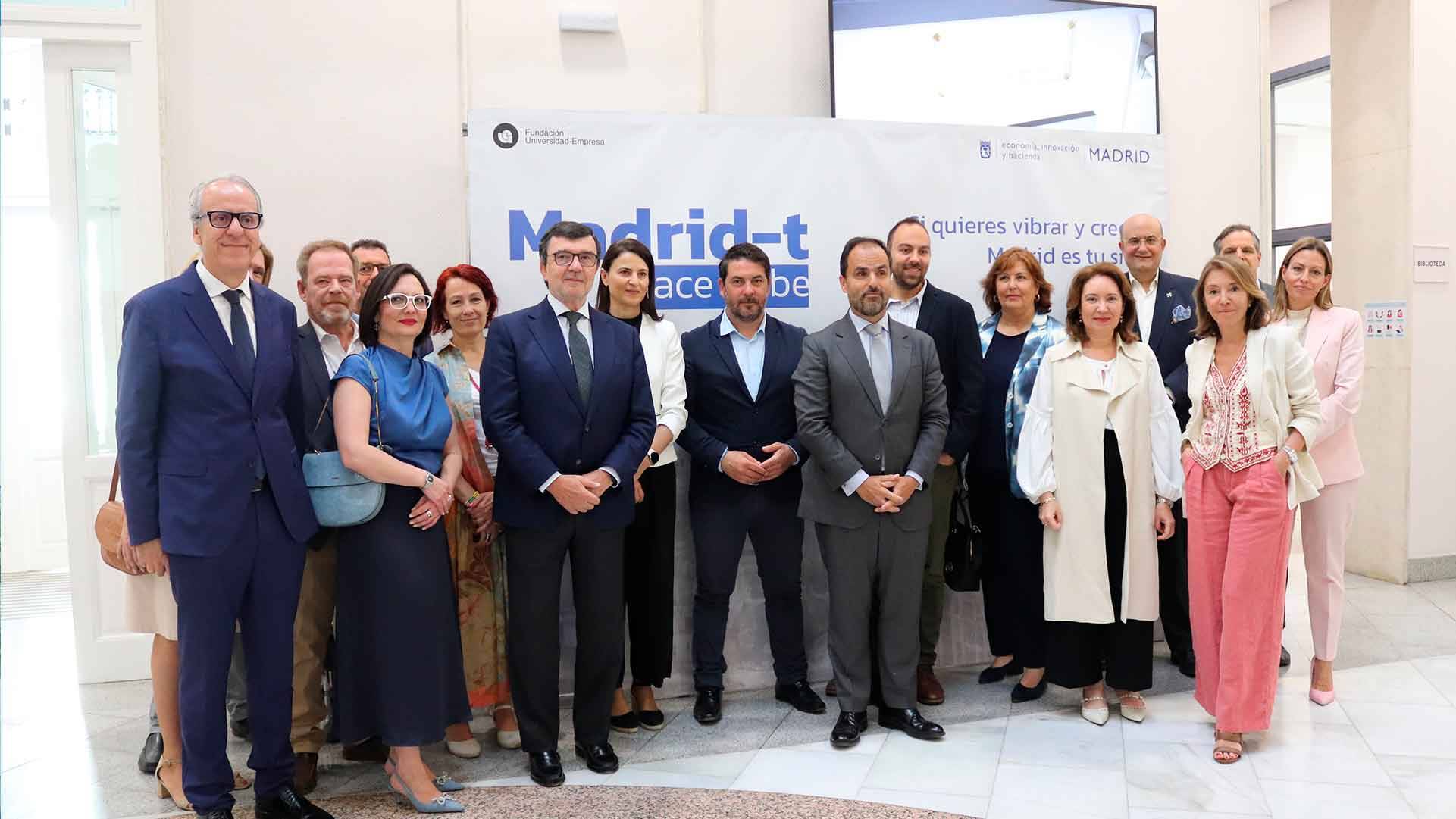 Un grupo de personas posando frente a un cartel que promueve la ciudad de Madrid.
