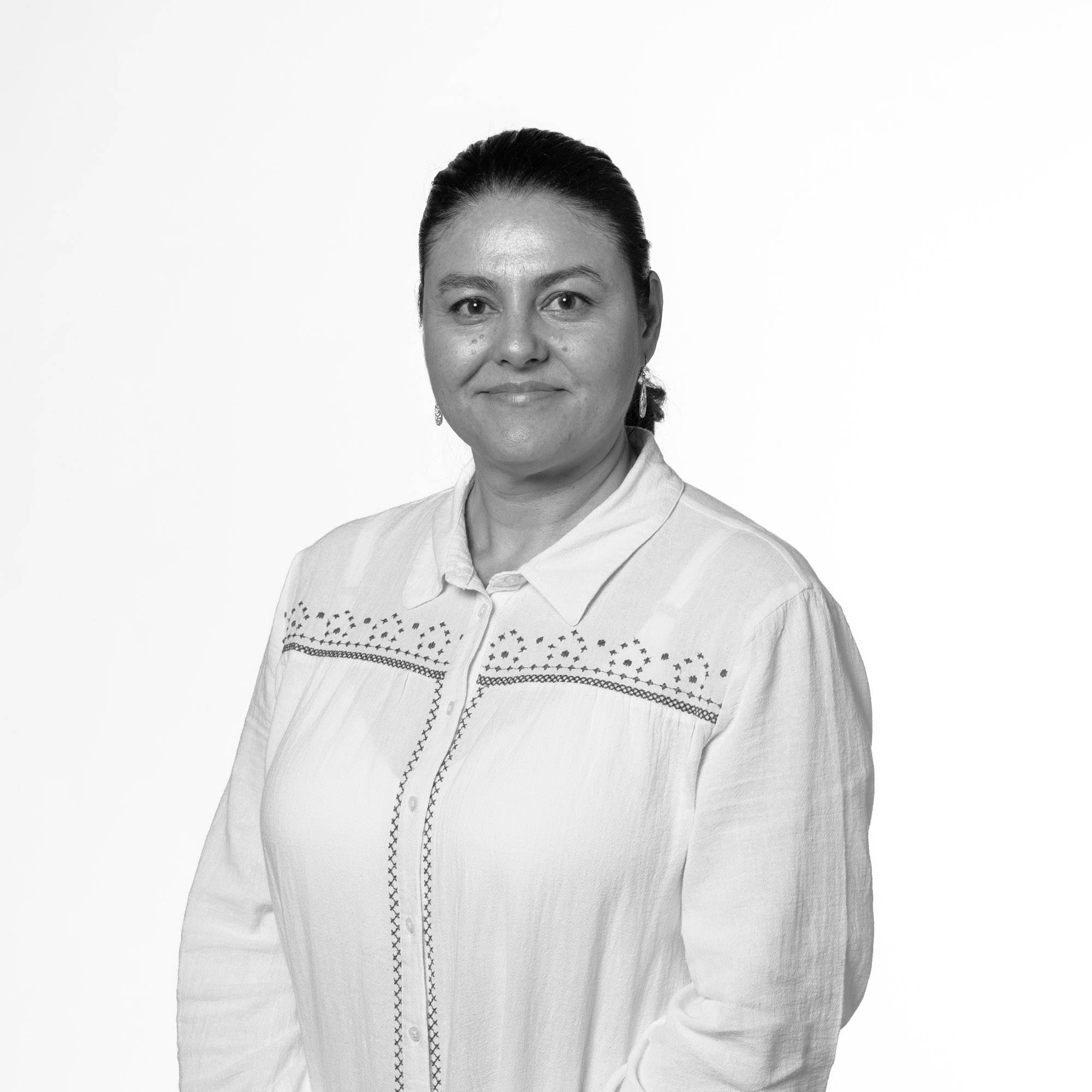 Retrato en blanco y negro de una mujer sonriente con blusa clara y cabello recogido.