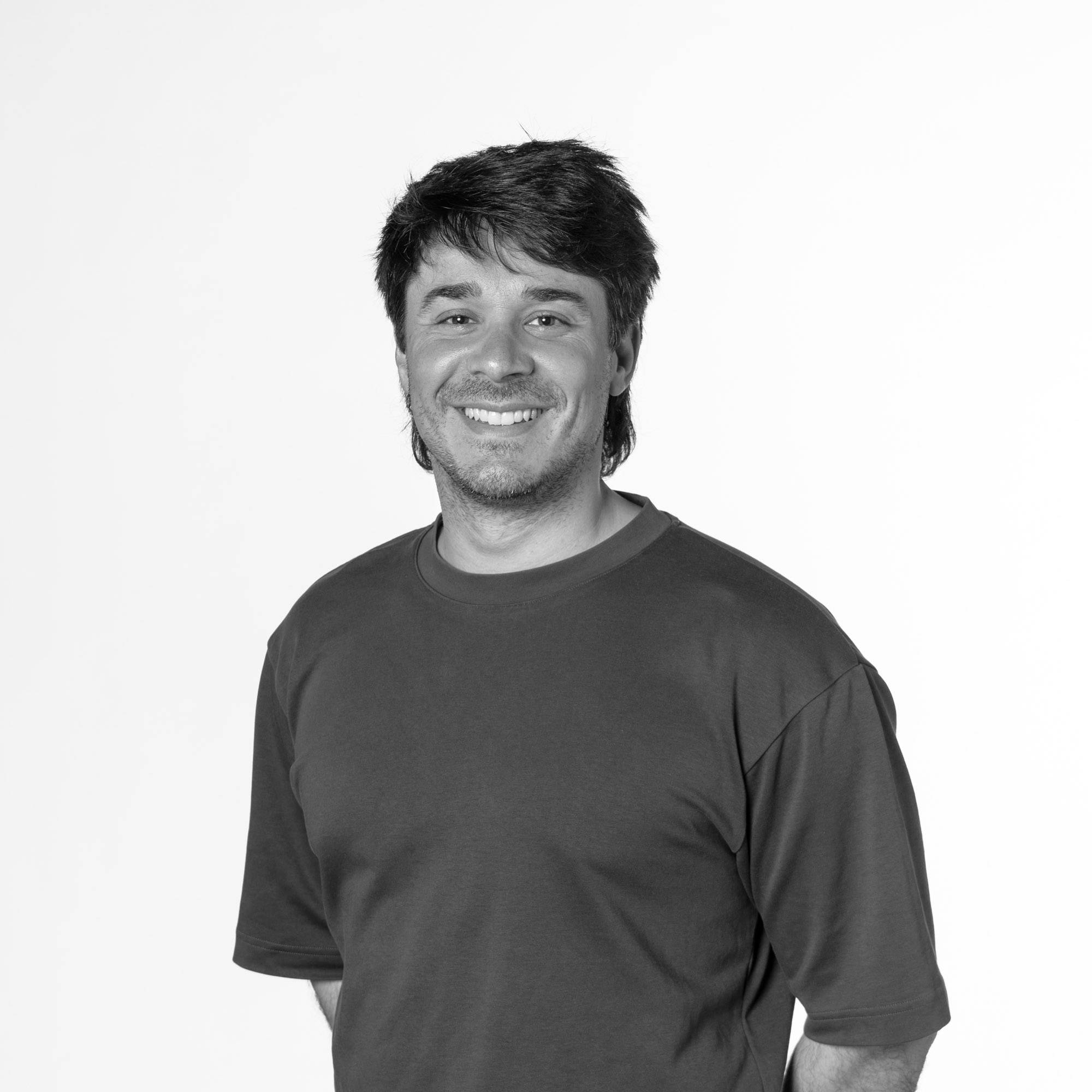 Un hombre sonriente posa frente a un fondo blanco.