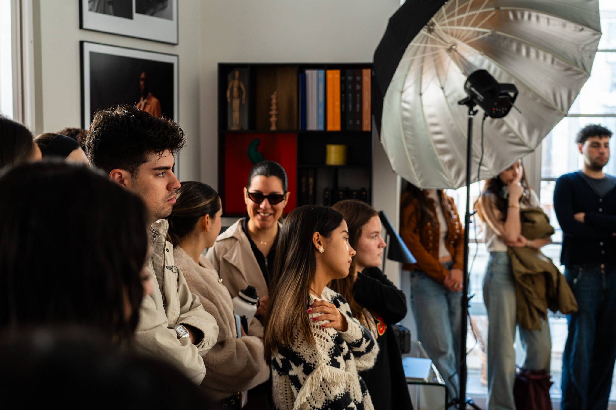 Un grupo de personas observa una sesión fotográfica en un ambiente luminoso y moderno.