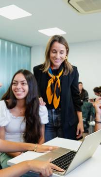 Un grupo de estudiantes discutiendo mientras trabajan en un ordenador portátil en un aula moderna.