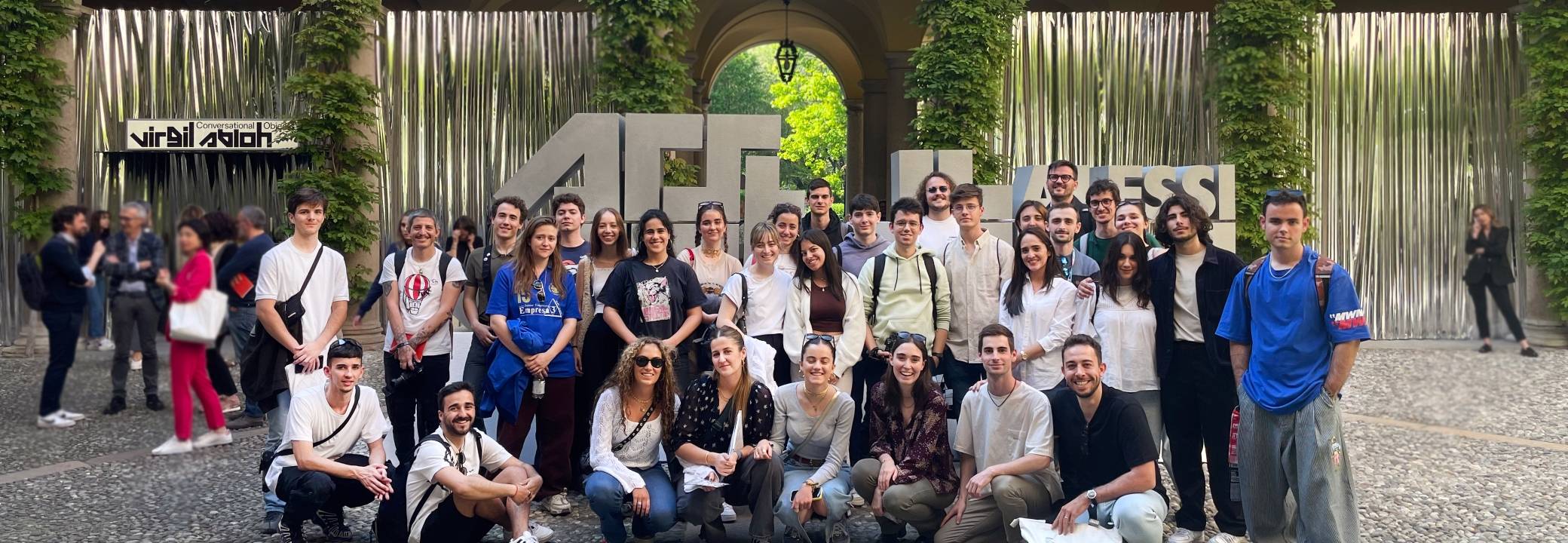 Un grupo grande de personas posando en un evento al aire libre con un fondo arquitectónico.
