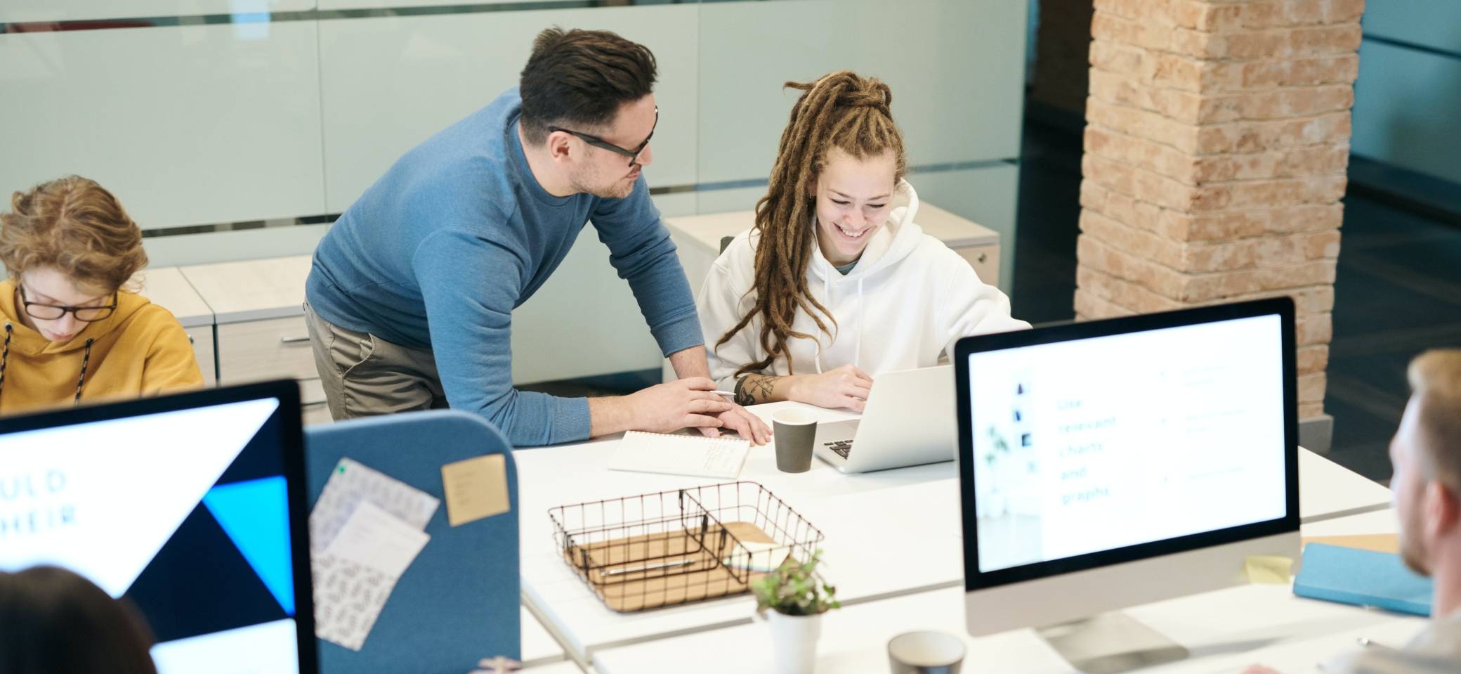 Una reunión de trabajo en una oficina moderna con varias personas colaborando en sus computadoras.