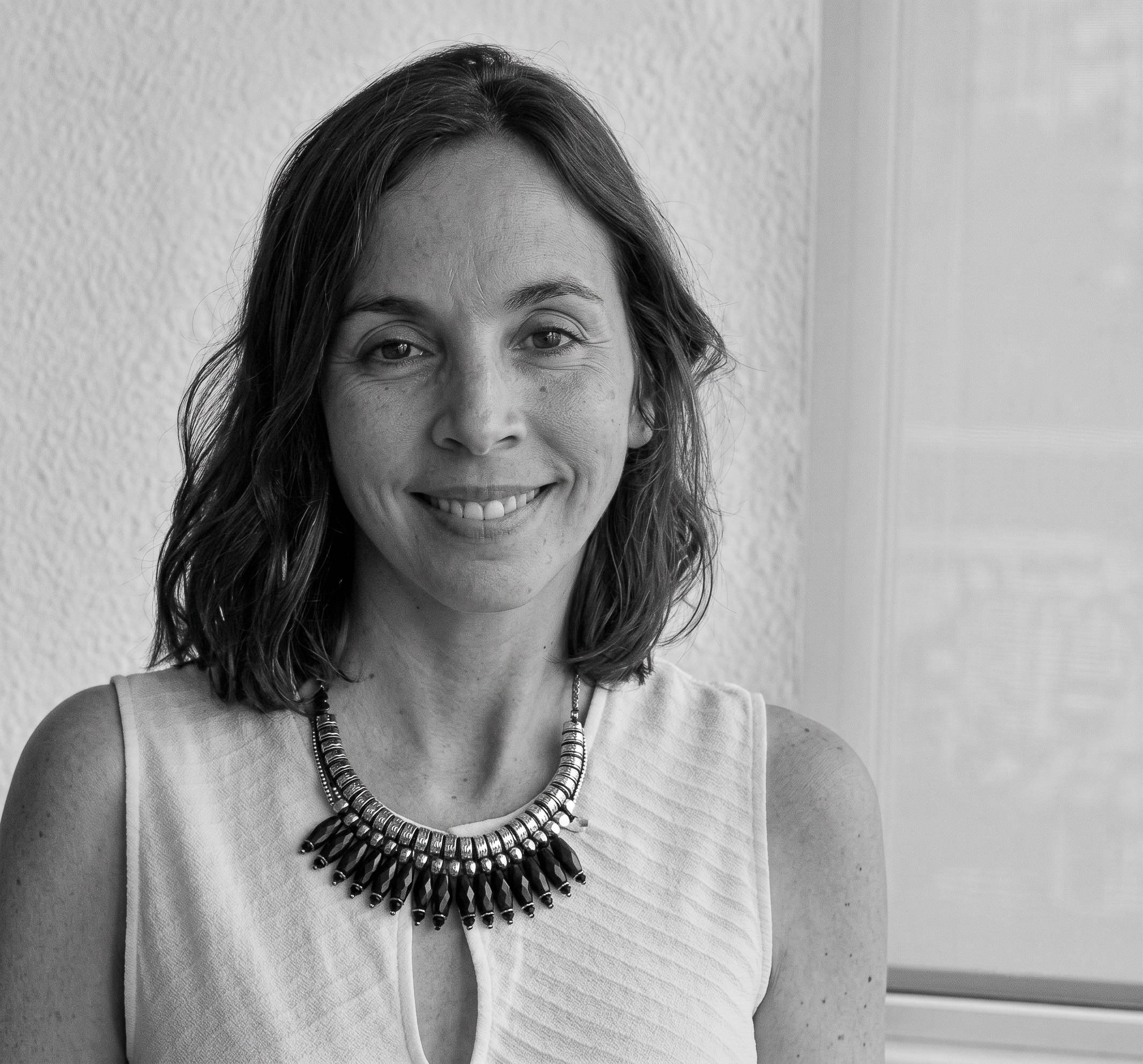 La imagen muestra a una mujer sonriente con un collar distintivo en un entorno luminoso.