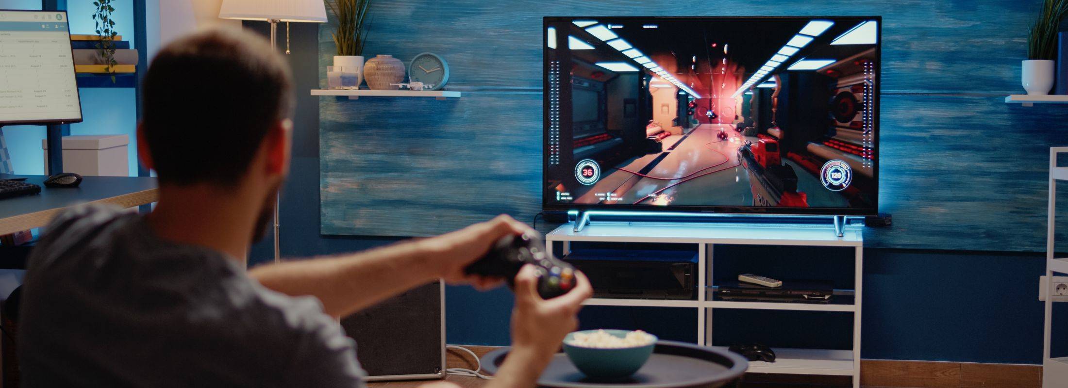 Una persona está jugando videojuegos en un televisor mientras sostiene un control en la mano.