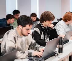 Un grupo de estudiantes concentrados en sus computadoras portátiles durante una clase.