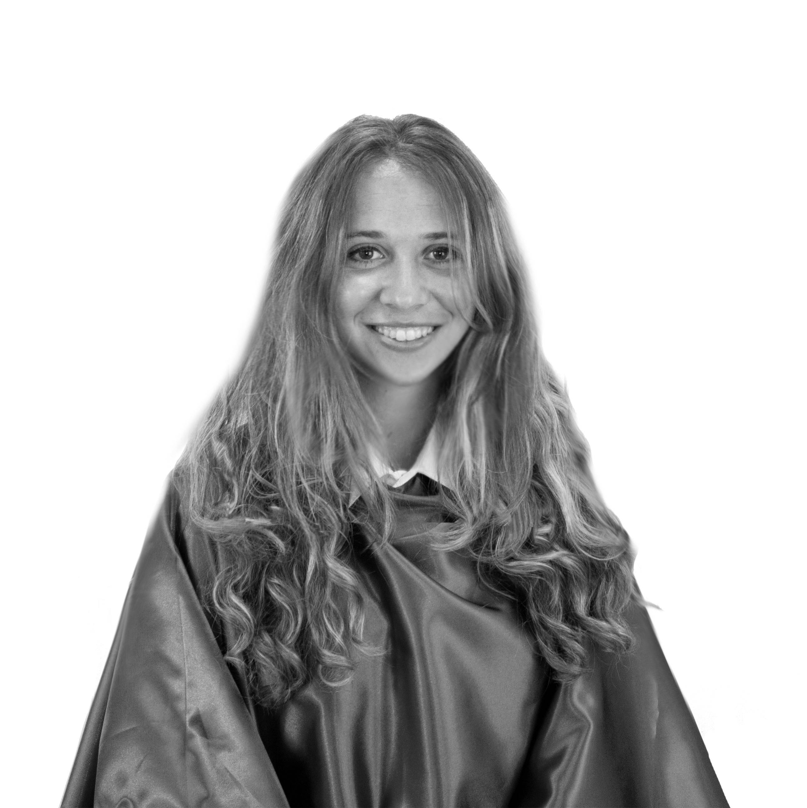 Mujer joven con cabello largo y rizado, sonriendo mientras lleva una capa.