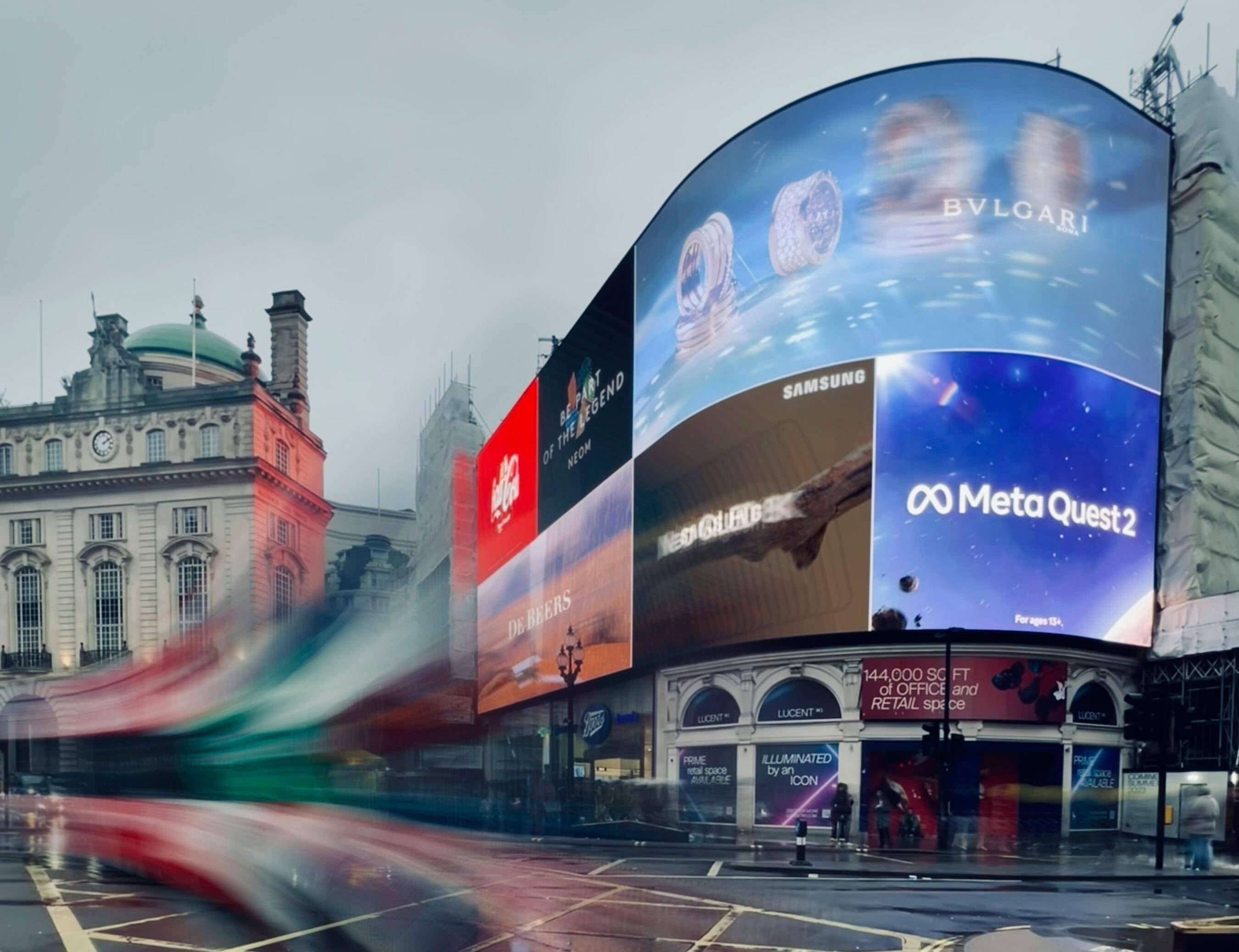 Una vista de Piccadilly Circus con pantallas publicitarias brillantes en un día nublado.
