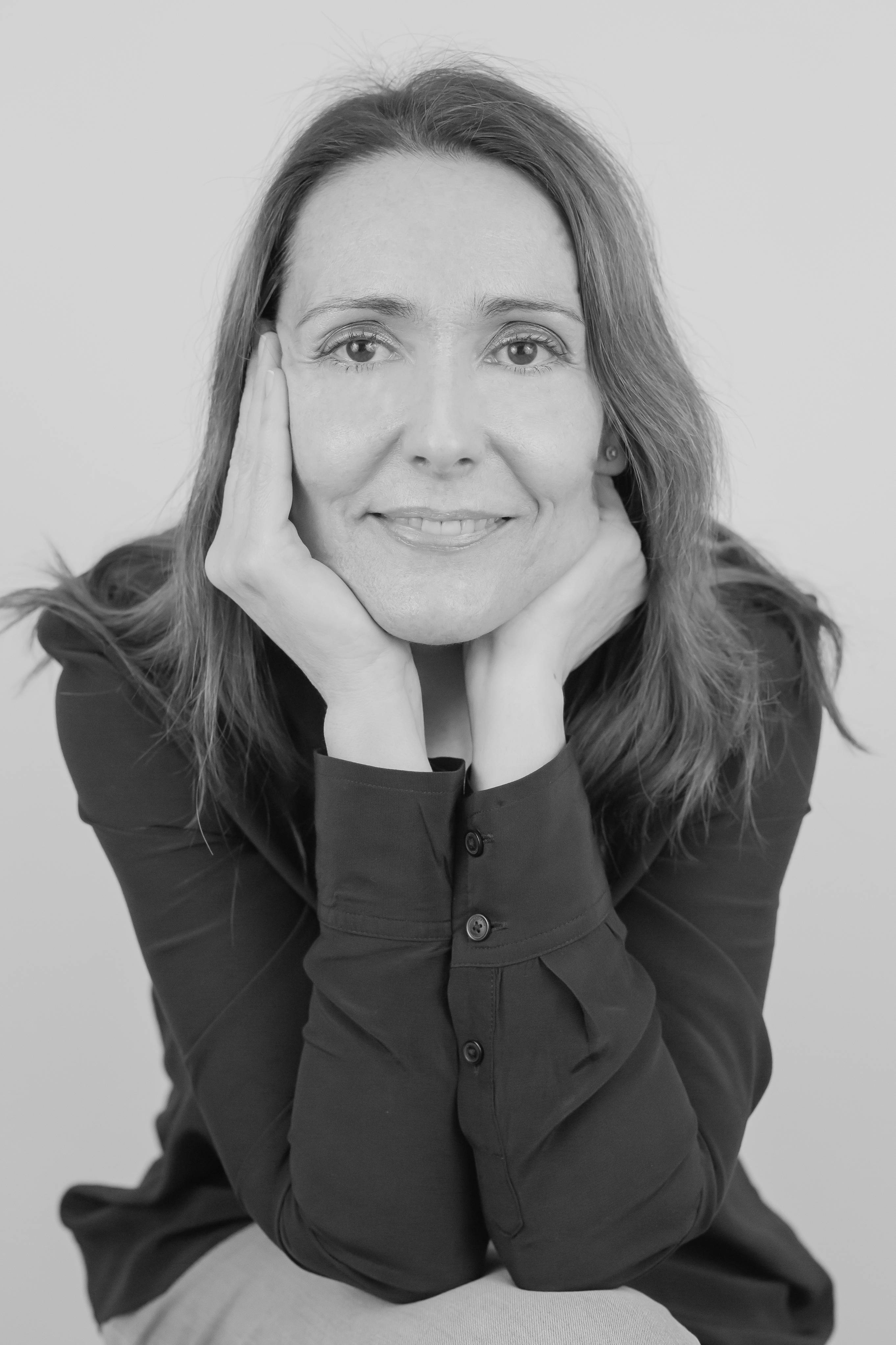 Una mujer sonriente posa con las manos en el rostro.