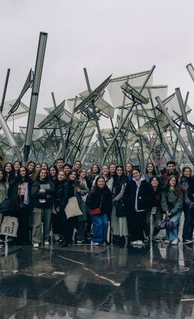 Un grupo grande de personas se reúne frente a una arquitectura contemporánea en un día nublado.