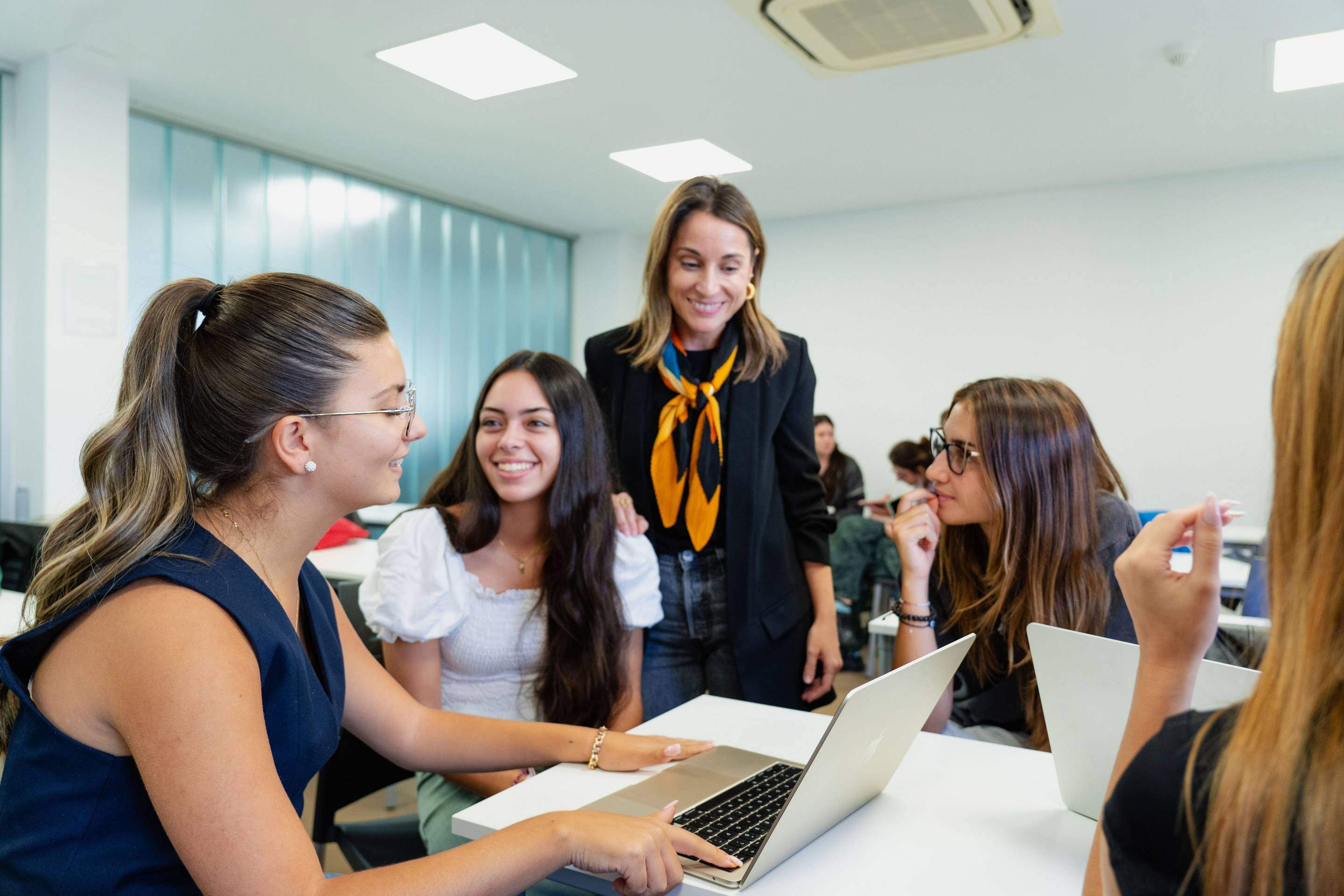 Un grupo de estudiantes discutiendo mientras trabajan en un ordenador portátil en un aula moderna.