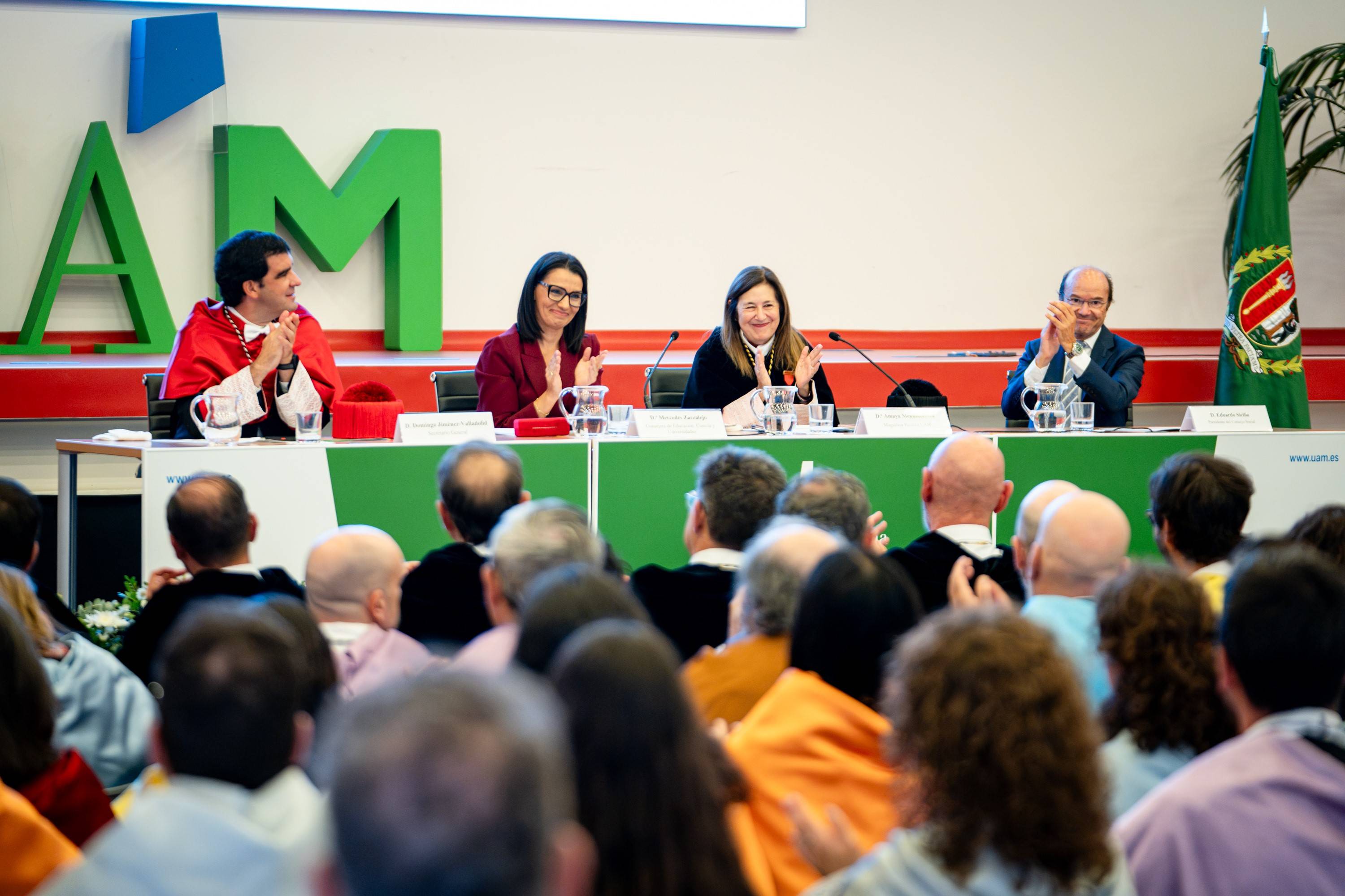 Una mesa de conferencias con varias personas aplaudiendo durante un evento formal.