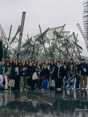 Un grupo grande de personas se reúne frente a una arquitectura contemporánea en un día nublado.
