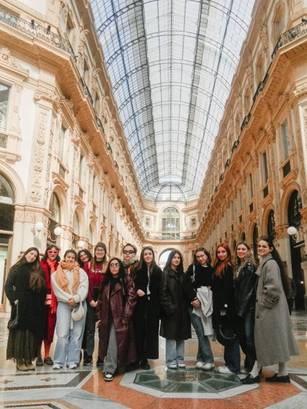 Un grupo de mujeres posa en un elegante pasillo de un centro comercial histórico con un techo de cristal.