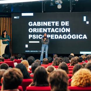 Una presentadora habla frente a una audiencia en un evento sobre orientación psicopedagógica.