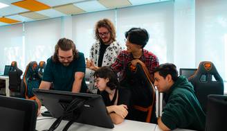 Un grupo de cinco personas se reúne alrededor de una computadora en un ambiente de oficina moderna.