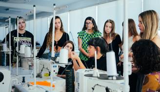 Un grupo de mujeres observa atentamente a una instructora en un taller de costura.