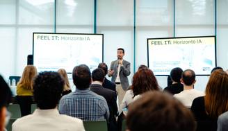 Un ponente está dando una charla sobre inteligencia artificial frente a una audiencia en un evento.