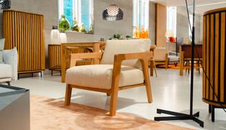 Sala de exhibición con muebles modernos y un sillón de madera clara.