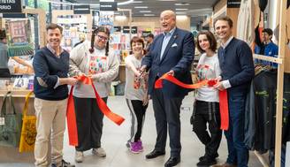 Inauguración de un evento con varios participantes sosteniendo una cinta roja.