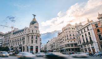 Una vista panorámica de un bullicioso cruce en Madrid con edificios históricos al fondo.