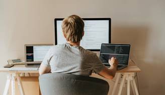 Una persona está trabajando en múltiples computadoras en un escritorio.