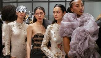 Un grupo de modelos luciendo trajes de diseño en un ambiente de ensayo de moda.