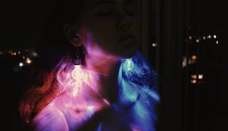 Una mujer con orejeras iluminadas que refleja luces de colores en un entorno oscuro.