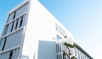 Edificio moderno con una fachada blanca y diseño minimalista bajo un cielo despejado.