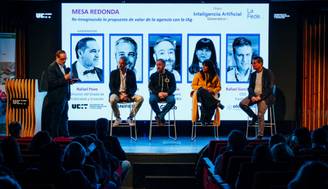 Una mesa redonda sobre inteligencia artificial con varios ponentes presentando en un escenario.