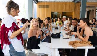 Un grupo de personas se reúne en una mesa mientras una mujer habla y los demás escuchan atentamente.