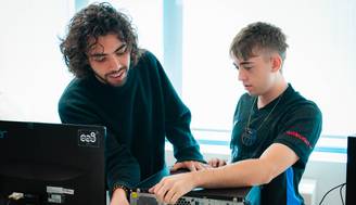 Dos jóvenes trabajan juntos en la parte trasera de una computadora de escritorio.