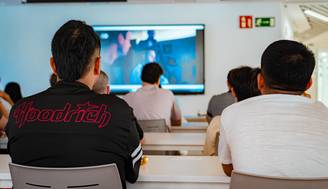 Un grupo de personas observando una presentación en una pantalla en un entorno académico.
